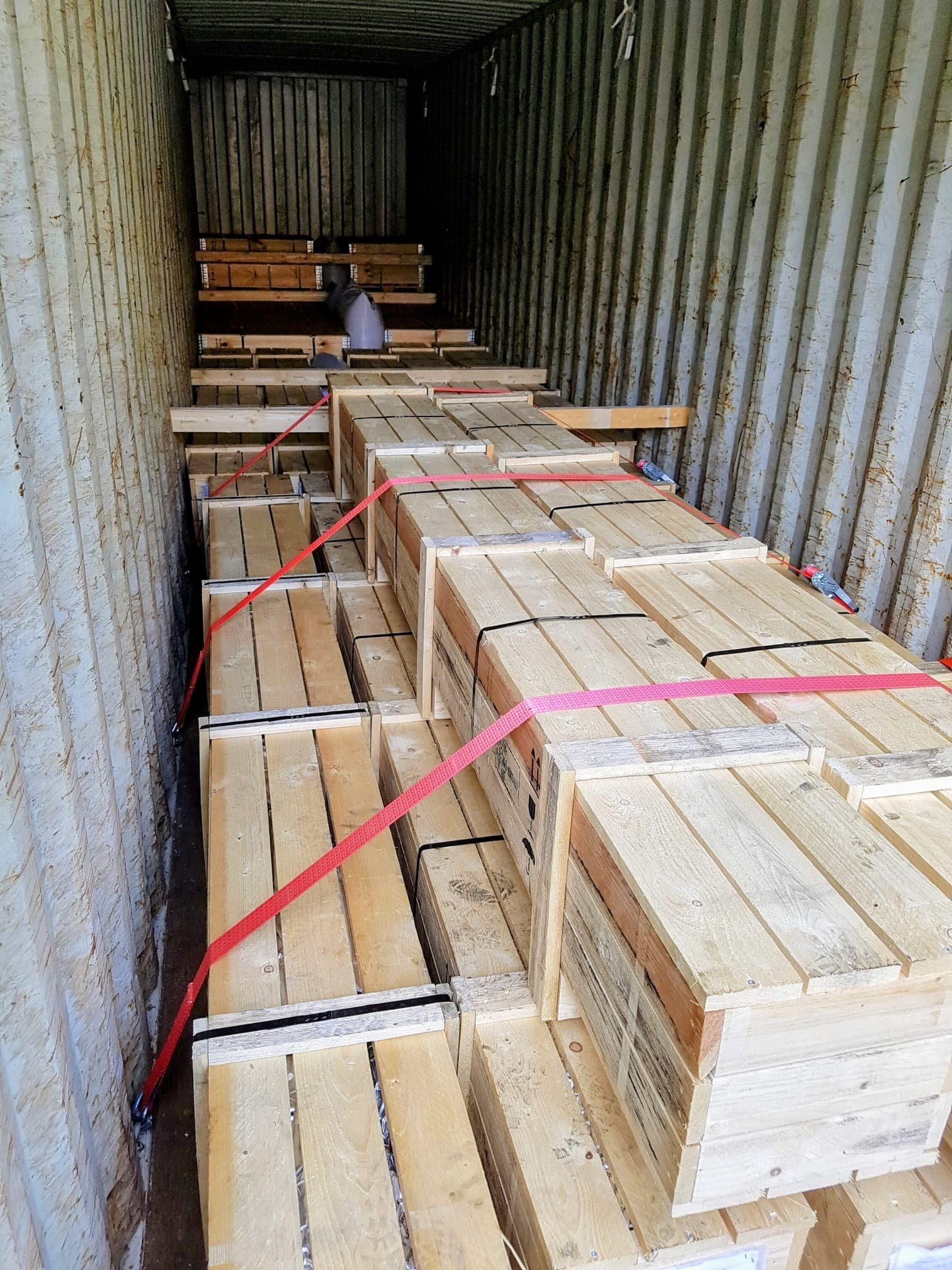 Containerstauung mit Stangenkisten und Zurrgurten